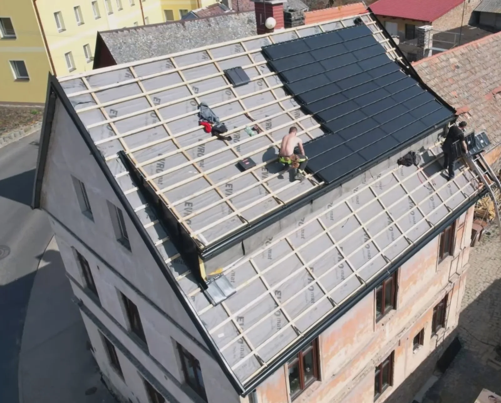 Dronový pohled na probíhající montáž moderních solárních tašek na střeše zrekonstruované kovárny.